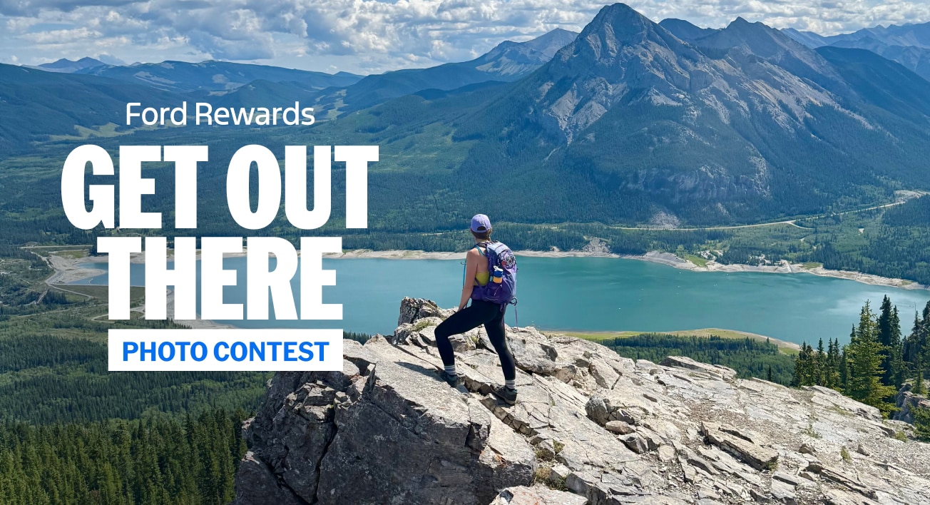 Woman on a rock ledge looking over a lake and mountain. "Ford Rewards. Get Out There. Photo Contest"