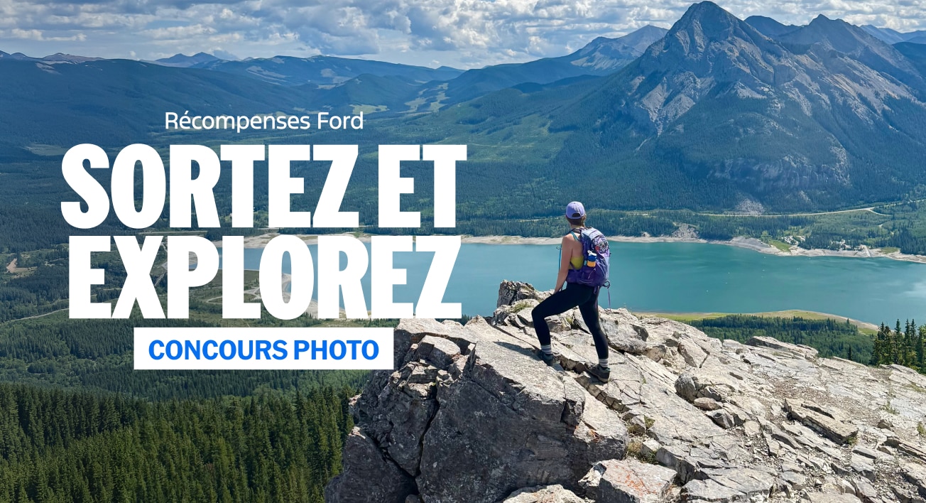 Femme sur un rebord rocheux regardant un lac et une montagne. "Récompenses Ford. Sortez et explorez. Concours photo."