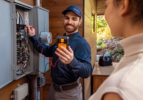 A Sunrun technician inspects an electric box outside of a home.