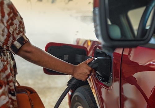 A woman plugs a charger into a Ford F-150 Lightning® truck.