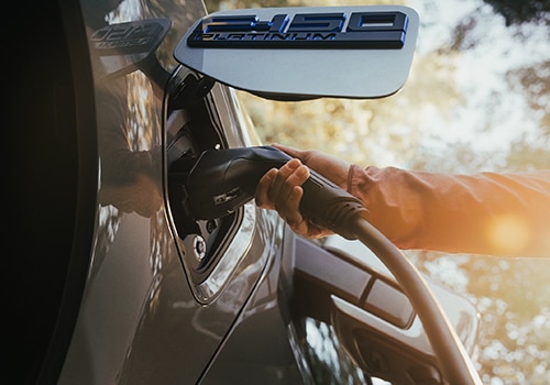A person plugs a charger into a Ford F-150 Lightning® truck.