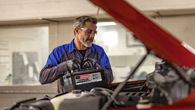 Technician with a battery and vehicle in a service bay