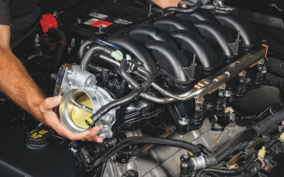 A Ford Service Technician holds an engine part.