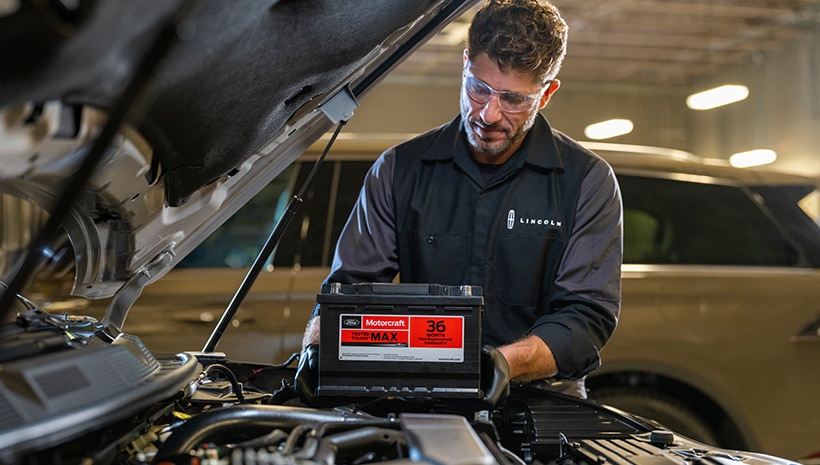 Técnico de servicio y una batería Motorcraft en una bahía de servicio