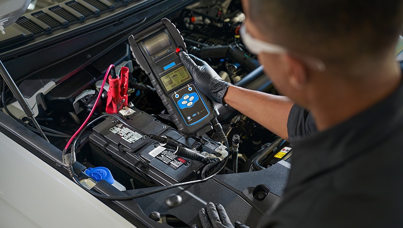 Service technician and a Motorcraft Battery in a service bay