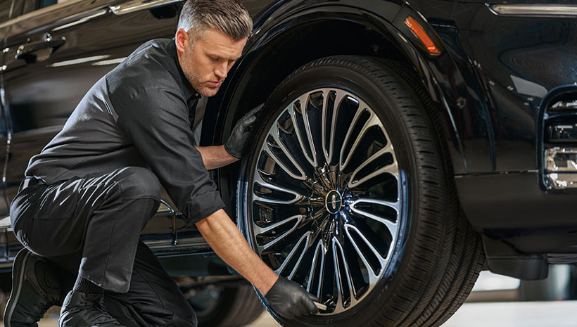 Service Technician with tire on a vehicle in a service bay