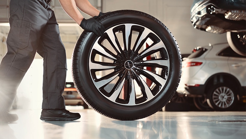 Service Technician rolling a tire in a service bay