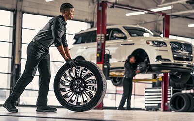 Technician rolling a tire in a service bay.