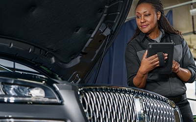 A Lincoln service tech is inspecting a vehicle.