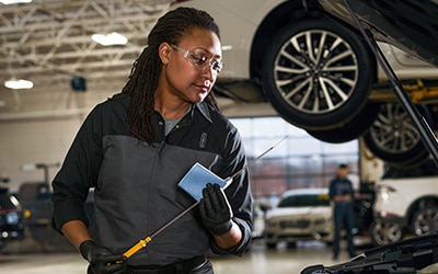 A Lincoln service tech is checking the oil on a vehicle.