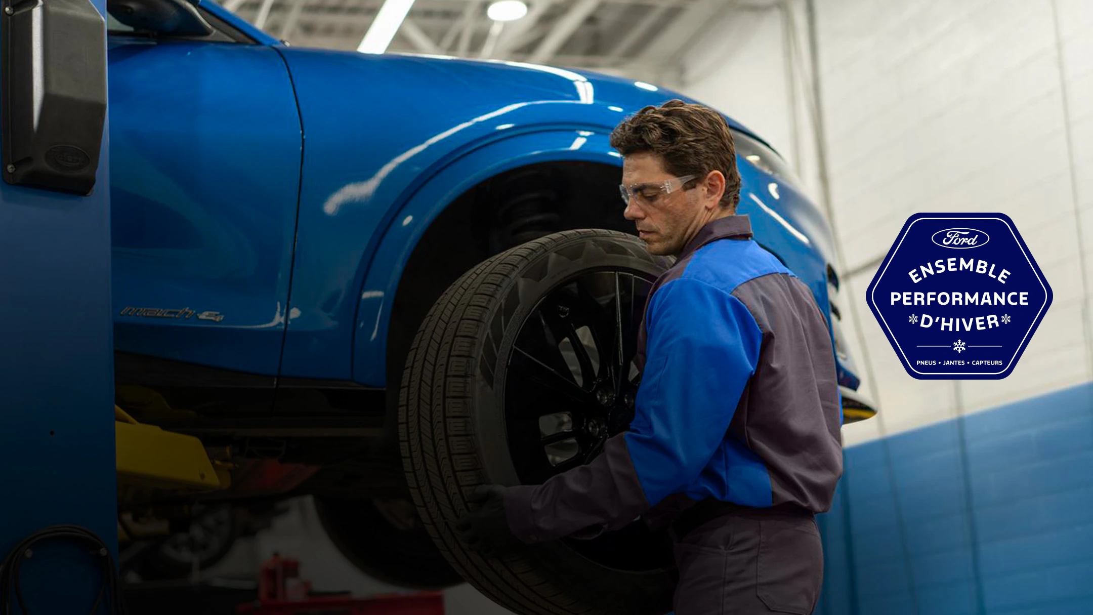 Un technicien formé par Ford installe un pneu sur une Mustang Mach-E bleue. À droite apparaît le logo de l’Ensemble performance hivernale Ford : pneus, jantes et capteurs.