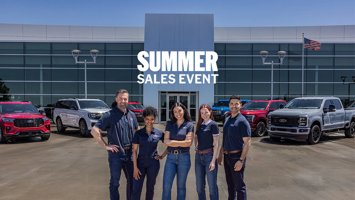Ford Dealers stand in front of a Ford lineup at the dealership.