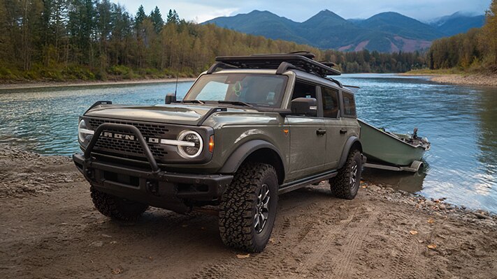 The Bronco® SUV reverses down a bank to drop a boat in the river.