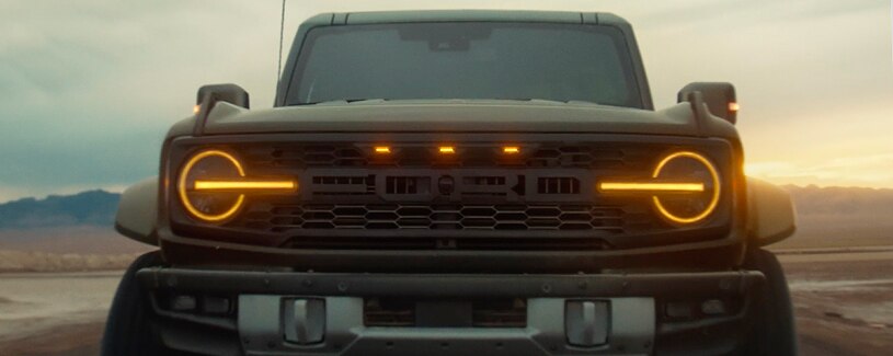 The Bronco® SUV’s grille lights up at dusk in the desert.