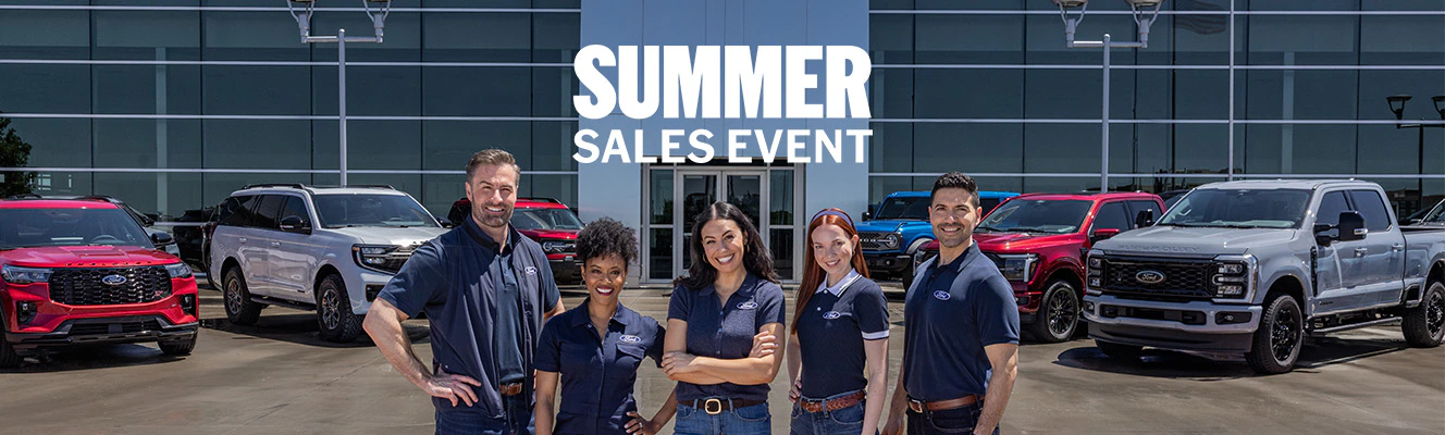 Ford Dealers stand in front of a Ford lineup at the dealership.